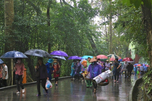 People under umbrellas offer incense to Hung Kings on the opening day of Hung Kings Festival