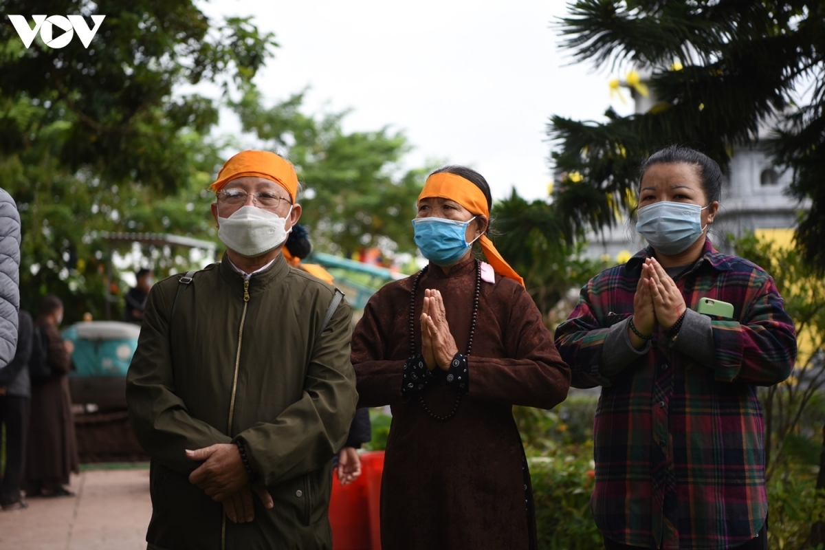 many buddhist followers stand outside in remembrance of the monk and his life.